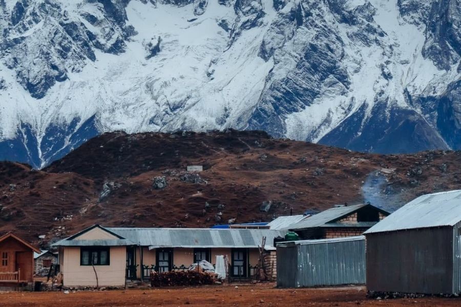 Basic mountain lodges with snow-capped peaks in background on Manaslu Circuit trek